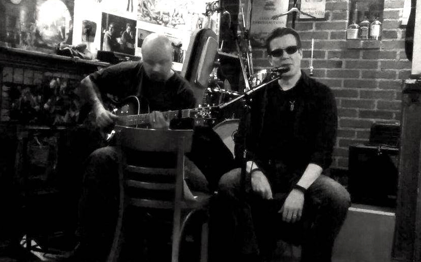 Kaksi muusikkoa, kitaristi ja laulaja esiintymässä ravintolassa.